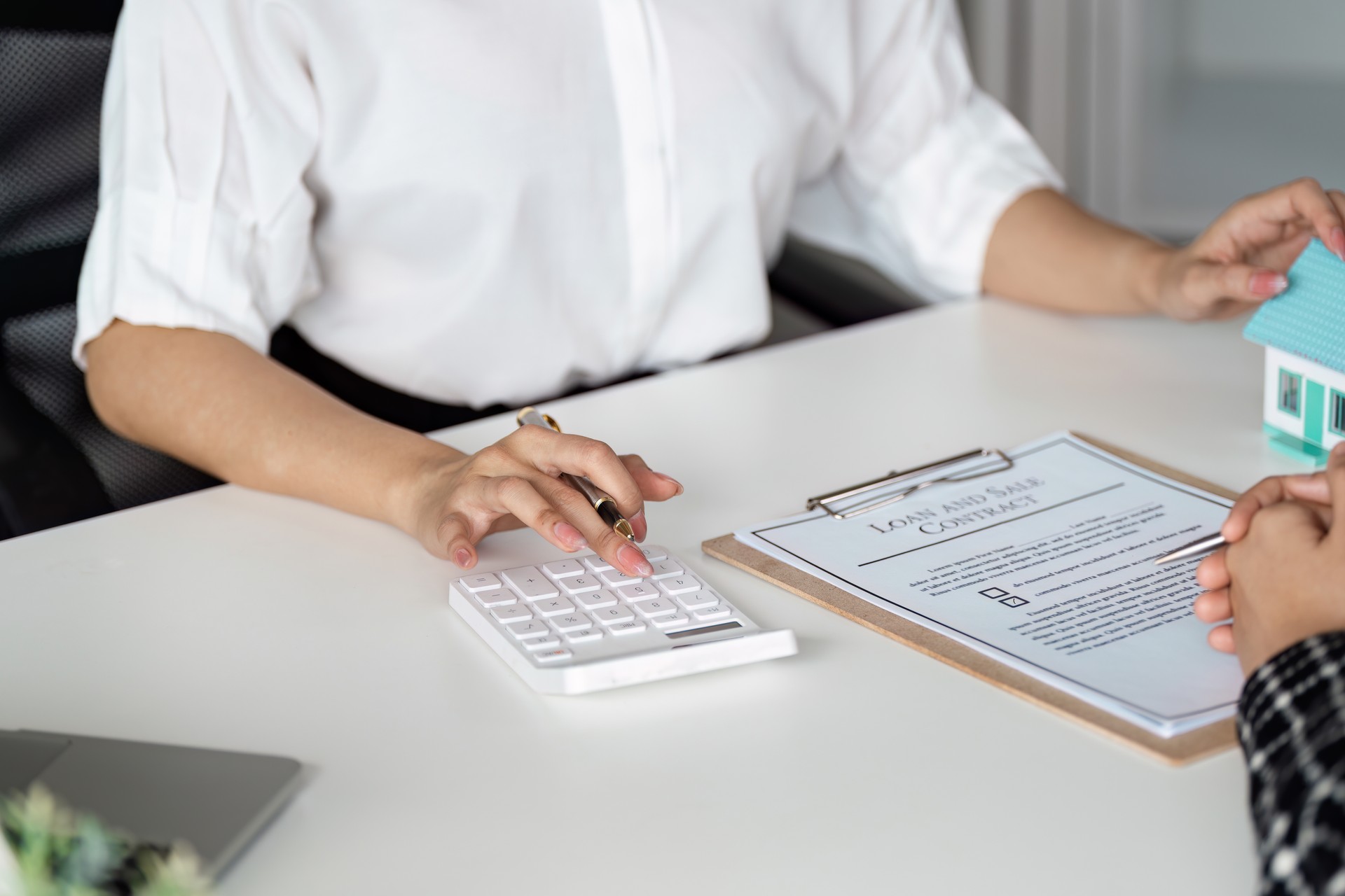 Real Estate Agent Calculating Mortgage Costs with Client, Loan Agreement on Desk